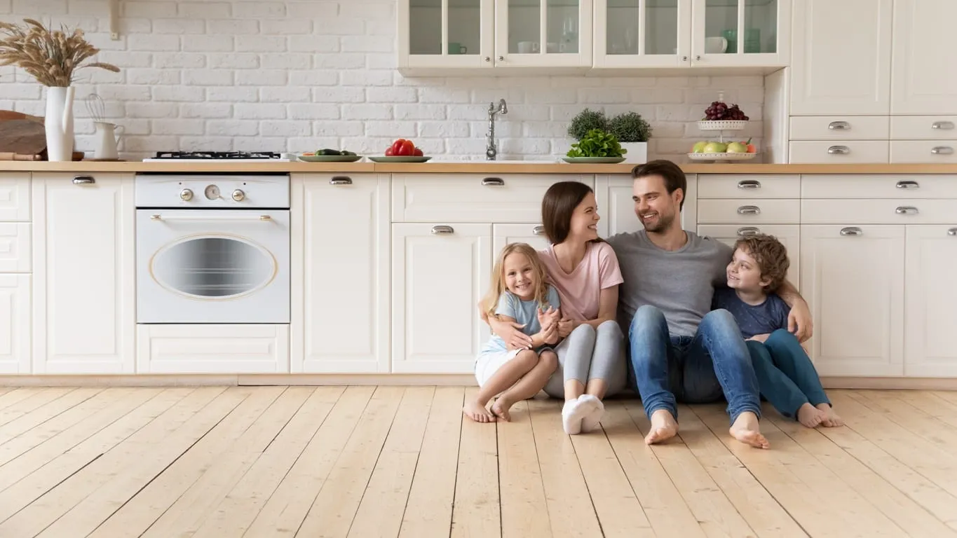 Familie sitzt auf warmem Holzboden in der Küche